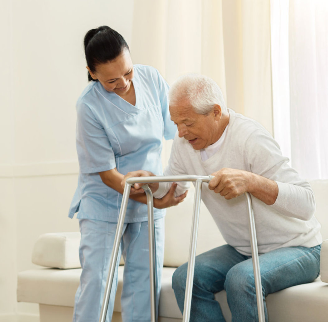 Cheerful caregiver smiling and helping her patient to stand up