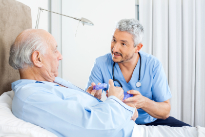 male caretaker explaining prescription to senior men in bedroom at nursing home