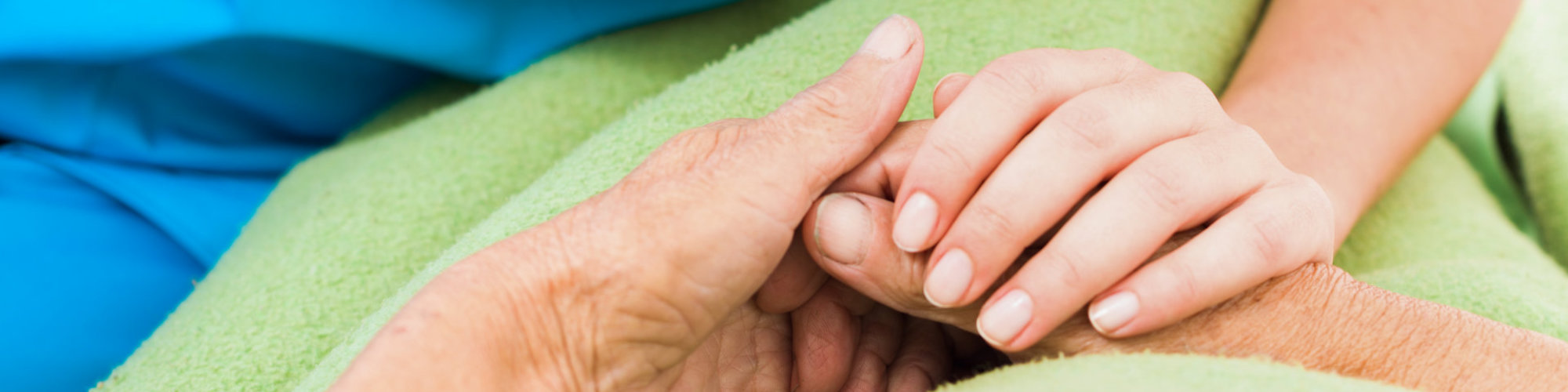 Social services nurse holding elderly woman's hand with care.