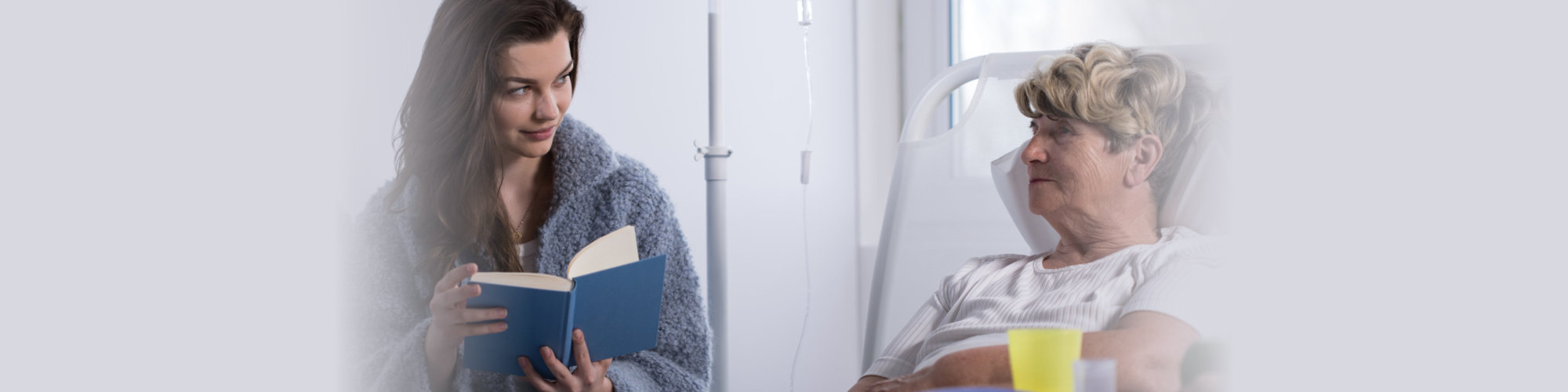 Woman reading a book to senior patient in hospice